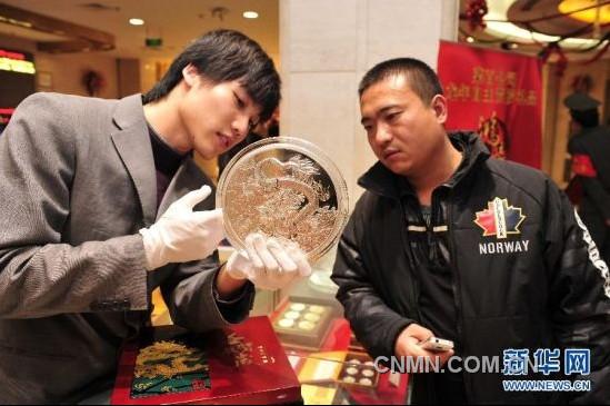 12月21日，工作人員向顧客介紹一款5公斤重的壬辰賀歲紀(jì)念大銀章，其正面的“金龍降喜”圖案，寓意對龍年萬事亨通的美好祝福。