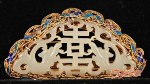 　　掐絲需具有靈巧的手上功夫，一把尖尖的鑷子，夾著一條纖細(xì)的銅絲，手指微微轉(zhuǎn)動(dòng)幾下之后，瞬間便化作朵朵金花、只只小鳥，以至湖光水色展現(xiàn)在器皿的胎型上時(shí)，無不為他們那絕妙高超的技藝而驚嘆。有很多白玉工藝品，使用這樣的高超工藝水準(zhǔn)配上溫潤(rùn)的和田玉，哪是一個(gè)精美絕倫可以形容的，他們之間絕配的魅力不知能吸引多少青年男女的青睞。 圖為 清銀掐絲鎏金琺瑯嵌玉胸花。全品。《概述》玉為雙螭拱“喜”。一周為銀掐絲鎏金琺瑯<國(guó)內(nèi)也有稱燒藍(lán)>背后有“SILVER”，胸花是鎖扣有經(jīng)驗(yàn)的行家都知道，民國(guó)以后基本就不做這樣鎖扣了。尺寸：38*69MM。