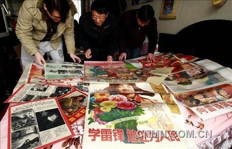 3月1日，房冠龍（中）在家中整理關(guān)于雷鋒的宣傳海報。