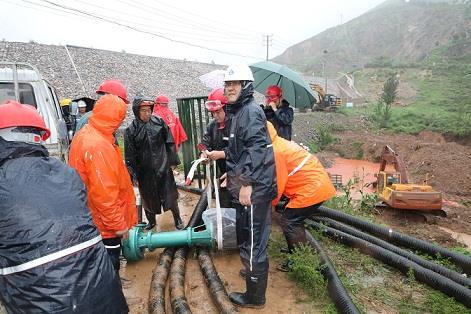 圖一為中州鋁業(yè)保障中心員工冒雨在現(xiàn)場搬運潛水泵設(shè)備，以應(yīng)對未來幾天更加嚴峻的汛情。
